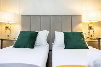 two beds with green pillows in a hotel room at Best Room Catone 21 in Rome