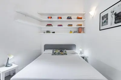 a white bedroom with a bed and white shelves at Colosseo Exclusive House by Premium Suites Collection in Rome