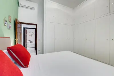 a bedroom with a white bed with red pillows and a mirror at Colosseo Exclusive House by Premium Suites Collection in Rome