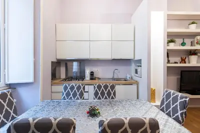 a kitchen with a table and chairs and white cabinets at Luxury Three Bedrooms flat in Roma Center in Rome