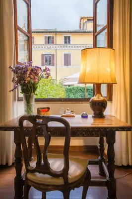 a table with a lamp and a vase of flowers at Palazzo Berardi: Renaissance Downtown Luxury Villa in Rome