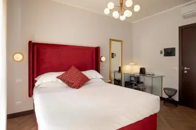 a bedroom with a large bed with a red headboard at Daplace - Hotel Gran Torino Suites in Rome