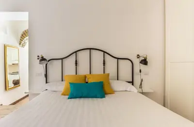 a bedroom with a large white bed with yellow and blue pillows at VII Coorte a Trastevere in Rome