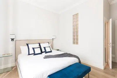 a bedroom with a large white bed with a blue bench at Idyllia - Elegant central flat in Rome