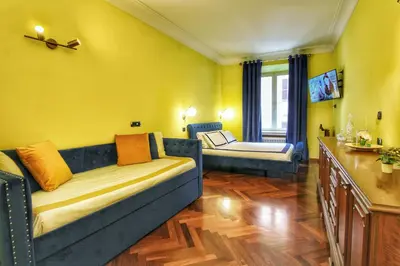 a living room with a blue couch and a yellow wall at Large and Charming Apartment in Trastevere by YourHost in Rome