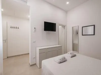 a white bedroom with a bed and a tv on the wall at The Best Rent - Two-bedroom apartment close to San Pietro in Rome