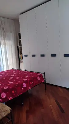 a bedroom with a bed with a red blanket and white cabinets at Montagnola House in Rome