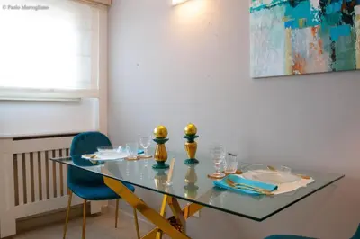a dining room table with blue chairs and a painting at Algima Flat Roma Ponte Milvio in Rome