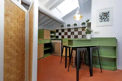 a kitchen with a green counter and stools at Monti Charme - My Extra Home in Rome