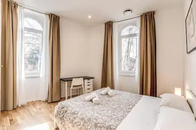 a bedroom with a bed and a desk and two windows at V E N E R E Apartments in Rome