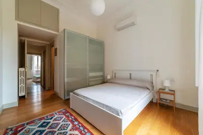 a bedroom with a large white bed and a rug at GuestHost - Bright & Roomy Apartment x6 - Trastevere District in Rome