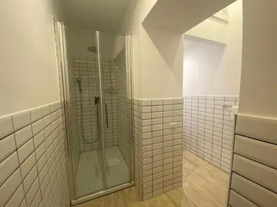 a bathroom with a glass shower and white tiles at Prestige Apartment Nazionale in Rome
