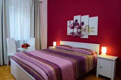 a bedroom with a red wall with a bed and two lights at B&B Eternal Rome Inn in Rome