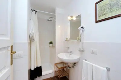 a white bathroom with a sink and a mirror at Cassiodoro19 in Rome