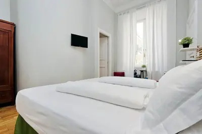 a white bedroom with two beds and a television at Cassiodoro19 in Rome