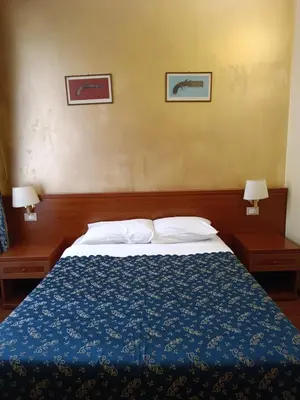 a bedroom with a bed with a blue blanket and two lamps at Opera Italian Suite in Rome