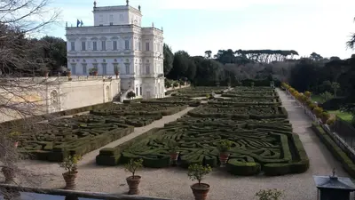 a garden with a large white building and a tower at Attico Monteverde in Rome