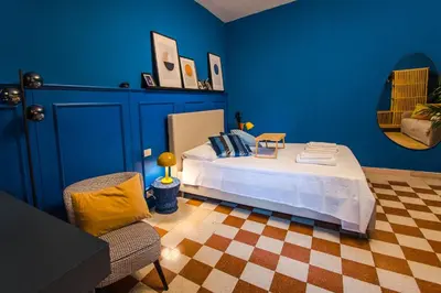 a blue bedroom with a bed and a chair at Telesio Suite in Rome