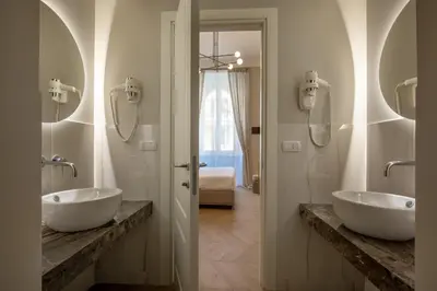a bathroom with two sinks and two mirrors at Porta Castello Suites in Rome