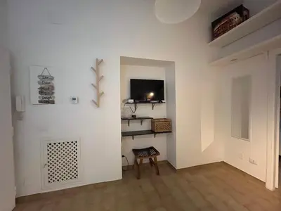 a white room with a chair and a tv on a wall at Appia Suite in Rome