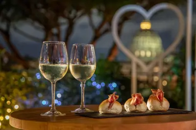 two glasses of white wine and three pieces of food at Fragrance Hotel St. Peter in Rome