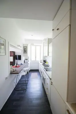 a kitchen with white cabinets and a black floor at Testaccio Luminous and Large Apartment in Rome