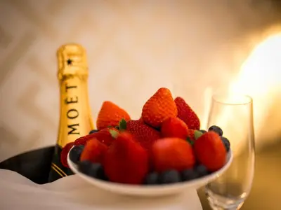 a bowl of fruit next to a bottle of champagne at Minerva Relais in Rome