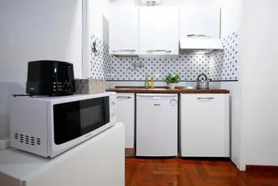 a kitchen with white cabinets and a microwave at Collection Spanish Steps Apartments in Rome