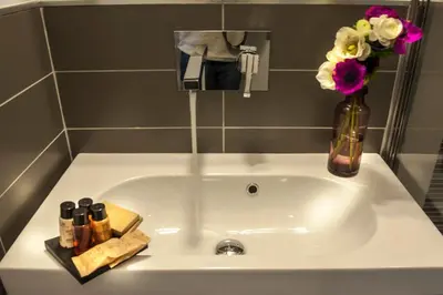 a white sink with a vase of flowers on it at DVE Suite Rome in Rome