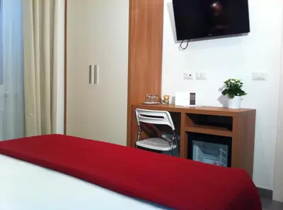 a hotel room with a desk and a bed with a red blanket at Holidays S.Lorenzo Guest House New in Rome