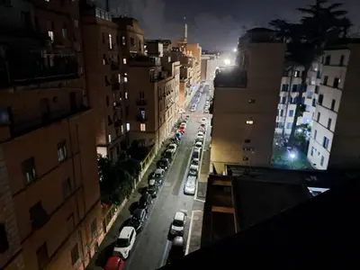a city street at night with cars parked at Holidays S.Lorenzo Guest House New in Rome