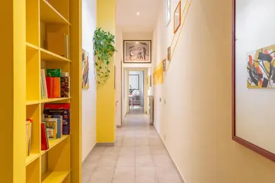 a corridor with yellow walls and a hallway with bookshelves at Casa Stella in Rome