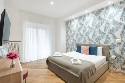 a bedroom with a bed with a blue and white wallpaper at White flat Gallia in Rome