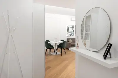 a white living room with a mirror and a table at White flat Gallia in Rome
