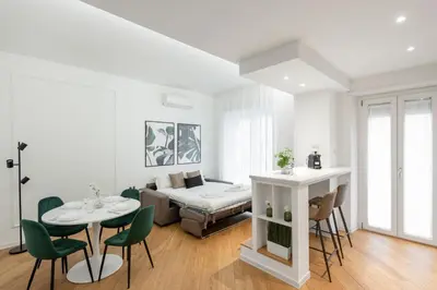 a living room with a bed and a table and chairs at White flat Gallia in Rome