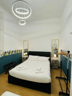 a bedroom with a large white bed and a chandelier at Bencò House in Rome