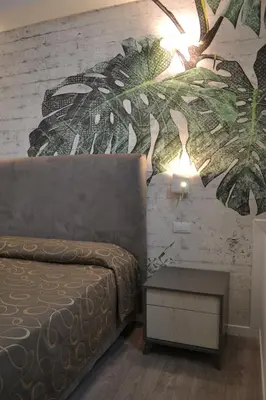 a bedroom with a bed and a table with a plant mural at Hotel Galileo in Rome