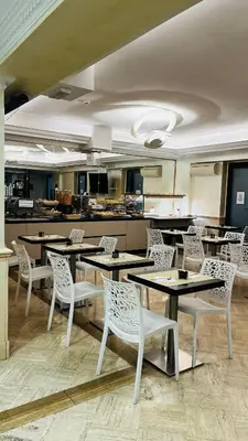 a dining room with tables and chairs and a kitchen at Hotel Galileo in Rome