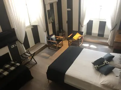 a bedroom with a bed and two chairs and windows at NEW! BELLISSIMO PalazzoFranchi Pantheon in Rome