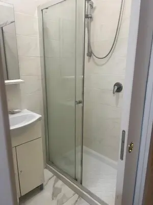 a shower with a glass door next to a sink at Termini Golden house in Rome