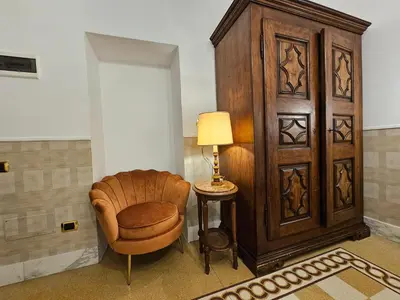 a room with a chair next to a large wooden cabinet at 4rooms In Rome in Rome