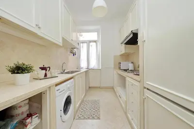 a kitchen with white cabinets and a washing machine at Sanctuary Home 32 in Rome