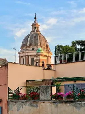 a building with a dome on top of a building with flowers at La Rosa di piazza Spagna in Rome