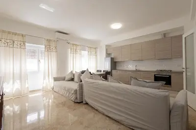 a living room with a white couch and a kitchen at Jmartins Vatican 2 in Rome