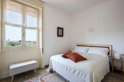 a white bedroom with a bed and a window at Refined upper-level apartment - Unique View of Rome's Skyline Tibernestrome in Rome
