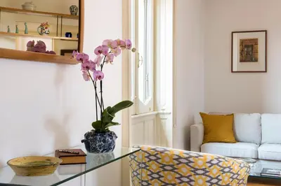 a living room with a glass table with a vase with purple flowers at Refined upper-level apartment - Unique View of Rome's Skyline Tibernestrome in Rome
