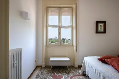a bedroom with a window and a bed and a chair at Refined upper-level apartment - Unique View of Rome's Skyline Tibernestrome in Rome