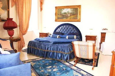 a bedroom with a blue bed and a chair at Charme Holidays Colosseum in Rome