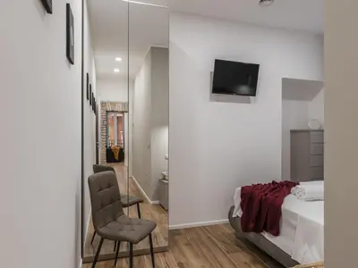a bedroom with a bed and a chair and a mirror at The Best Rent - Modern three-bedroom apartment a few steps from the Colosseum in Rome