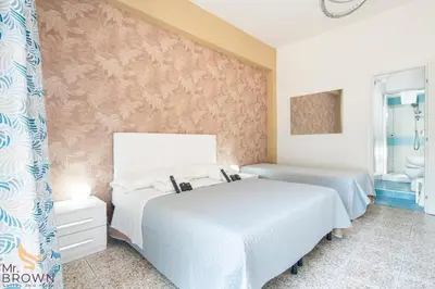 a bedroom with two beds and a wall with pink wallpaper at Mr. Brown - Marconi in Rome